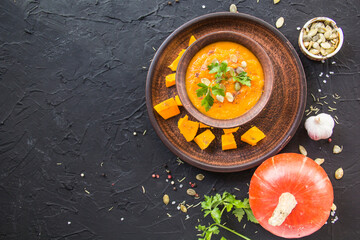 Delicious healthy pumpkin soup, herbs, and ingredients for the dish. Creative atmospheric decoration