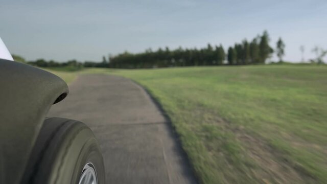 low angle shot of golf car wheel riding along the road inside green golf course, sports relax in holidays summer vacation, spring valley, close up wheel, difference perspective, hot sunny weather