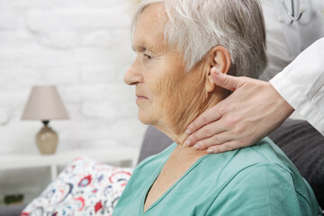 Doctor examining senior woman's thyroid glands or tonsils.