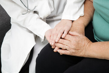 A friendly doctor holding seniar patient’s hand for encouragement, empathy and support following...