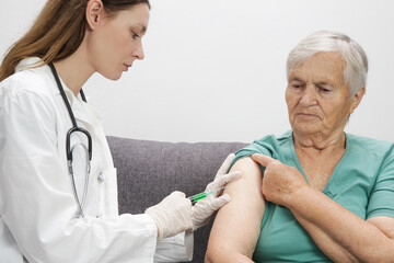 Senior woman receiving vaccine. Medical worker vaccinating an elderly patient against flu, influenza, pneumonia or coronavirus.