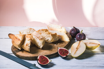 Baguette, figs and pears lie on a white wooden table. Food and meal concept