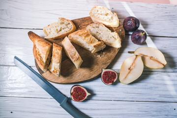 Baguette, figs and pears lie on a white wooden table. Food and meal concept