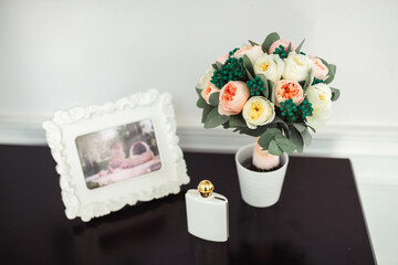 Composition on the table of a bouquet of roses and a white frame in defocus