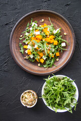 Delicious healthy pumpkin salad with arugula and cheese. Creative atmospheric decoration