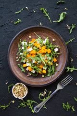 Delicious healthy pumpkin salad with arugula and cheese. Creative atmospheric decoration