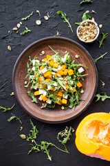 Delicious healthy pumpkin salad with arugula and cheese. Creative atmospheric decoration
