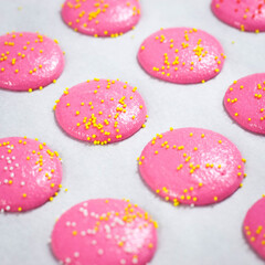 Pink French Macarons with Yellow Sprinkles on Baking Sheet with White Parchment Paper