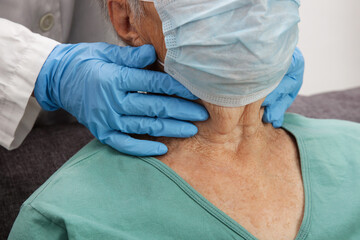 Fototapeta premium Doctor examining senior woman's thyroid glands or tonsils.