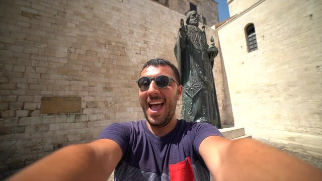 happy man tourist visiting Apulia region and taking selfie in the main square of the old town of Bari 