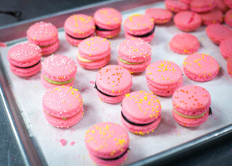 Pink French Macarons with Yellow Sprinkles on Baking Sheet with White Parchment Paper