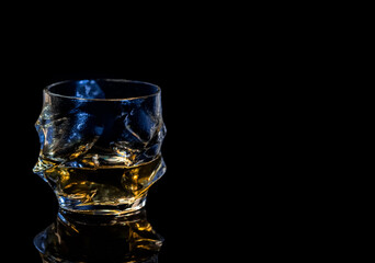 barman pouring whiskey in front of whiskey glass and bottles on black table with reflection