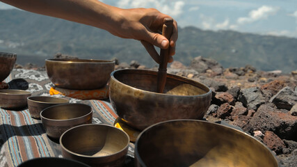 Asian guy playing Tibedt singing copper cups on a viewing mountain