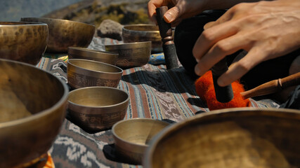 Asian guy playing Tibedt singing copper cups on a viewing mountain