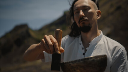 Asian guy playing Tibedt singing copper cups on a viewing mountain