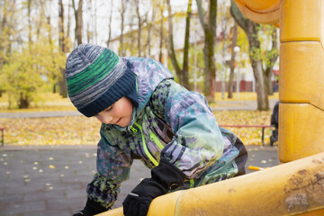 boy in late autumn playing in city park, season change concept, happy childhood.