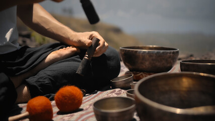 Asian guy playing Tibedt singing copper cups on a viewing mountain