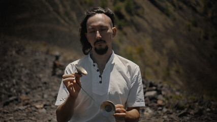 Asian guy playing Tibedt singing copper cups on a viewing mountain