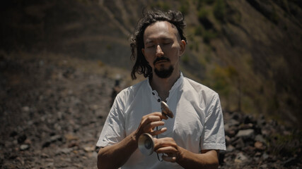 Asian guy playing Tibedt singing copper cups on a viewing mountain