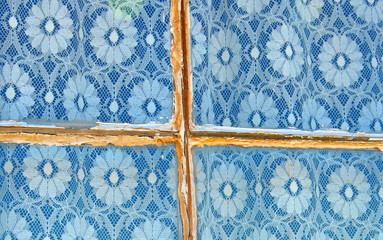 Lace Curtains - Window frame - A beautiful pattern of lace curtains hung behind an old weathered window frame 