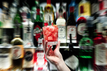 cocktail in hand on backbar background negroni