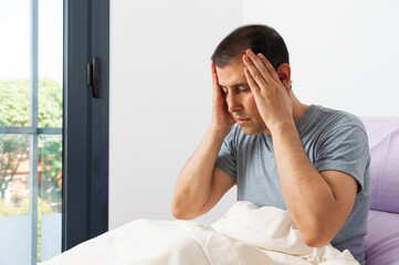Shot of a young man suffering migraine complaining in his bedroom
