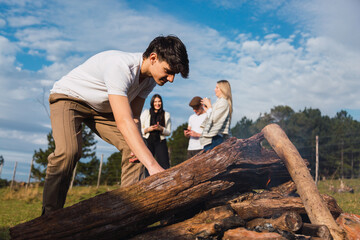 Young man having fun at a fire picnic. Group of young friends enjoying the outdoors.
