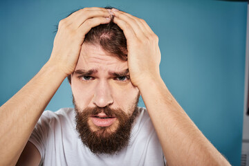 Bearded man displeased facial expression emotions close-up blue background white t-shirt