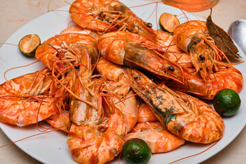 Red cooked prawns on a white plate with vegetables.