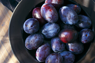 Fresh blue plums in black plate