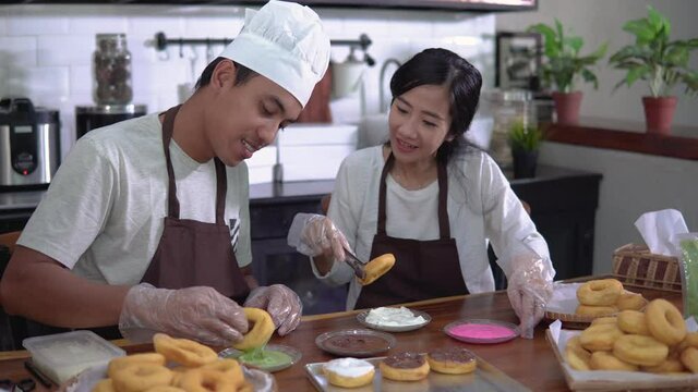portrait of asian couple working on their small business by making handmade food bakery and donuts product at home