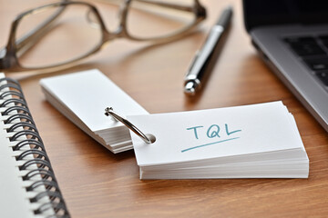 The words "TQL" written in a word book. Close-up. It is an acronym for "Teleprospecting Qualified Leads".
