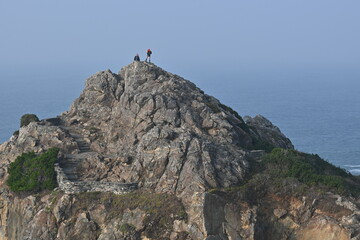 People on rock over ocean