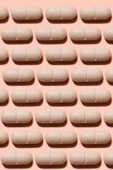 Drug pattern. Repeating beige pills on a beige background. Textured background of beige pills lying in a row. Vertical, close-up, macro.