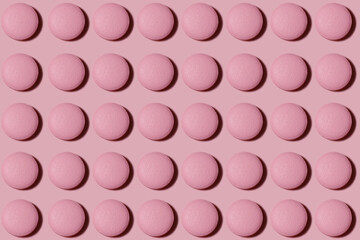 Drug pattern. Repeating pink pills on a pink background. Textured background of pink round pills lying in a row. Health concept.
