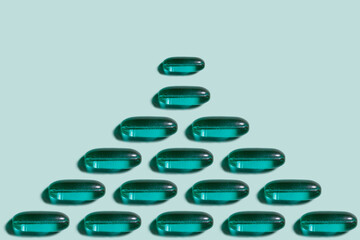 Drug pattern. Repetition of green capsules on a light green background. Textured background of pills lying in a row. Abstract green background.Health concept.