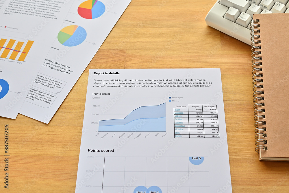 Poster there is a white keyboard and a piece of paper with a line graph stacked with a notebook and pen.