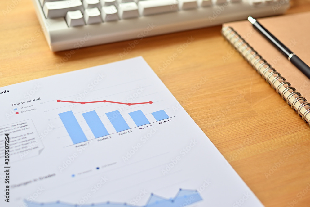 Poster there's a piece of paper with a downward trending line and a bar chart on it, along with a white key