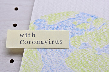 There is a sketchbook with an illustration of the earth and a sticky note with the words "with Coronavirus" on it.