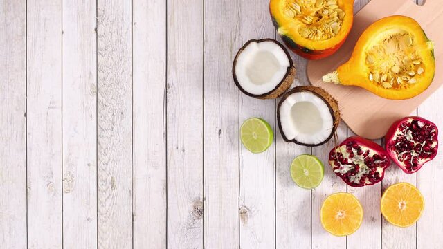 Moving sliced pumpkin, coconut, lime, orange and pomegranate on wooden theme. Stop motion 
