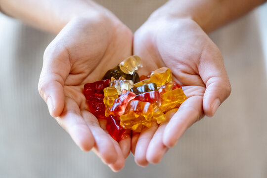 Closeup image of a woman holding colorful jelly gummy bears in hands