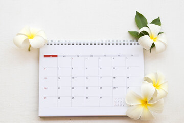 calendar month planner with white flower frangipani decoration flat lay style on background white 