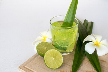 herbal healthy drinks pandan and lemon cocktail water with lemon slice ,frangipani flowers decoration flat lay style on background white wooden