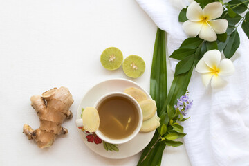 herbal healthy drinks ginger syrup cocktail water for health care with lemongrass ,ginger slice ,lemon slice ,pandan leaf and flower frangipani decoration flat lay style on background white wooden