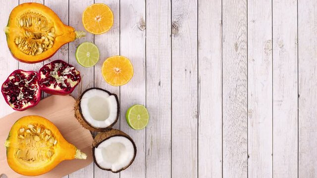 Sliced tropic and citrus ripe fruits appear on left side of wooden theme. Stop motion 
