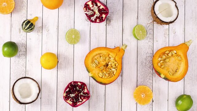 Sliced tropic and citrus fruits appear on light wooden theme. Stop motion 