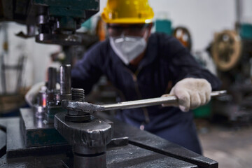 Engineer repair heavy machine with big wrench and focus on wrench and nut in industry manufacturer