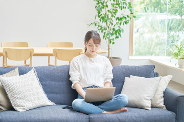 Fototapeta premium リビングでパソコンを使う女性