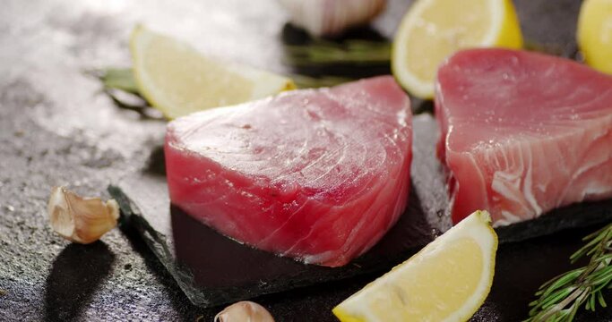 Tuna raw steaks on a stone board with garlic and lemon rotate. 