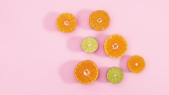Slices of oranges and limes appear on pastel pink theme. Stop motion 